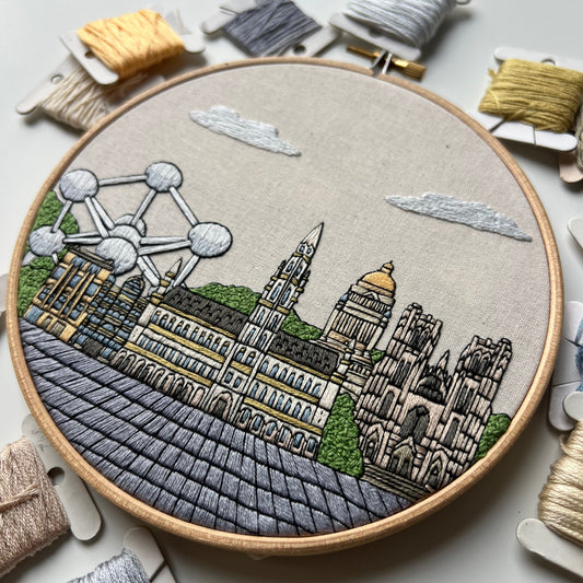 Embroidery hoop with a detailed Brussels cityscape design on a light background