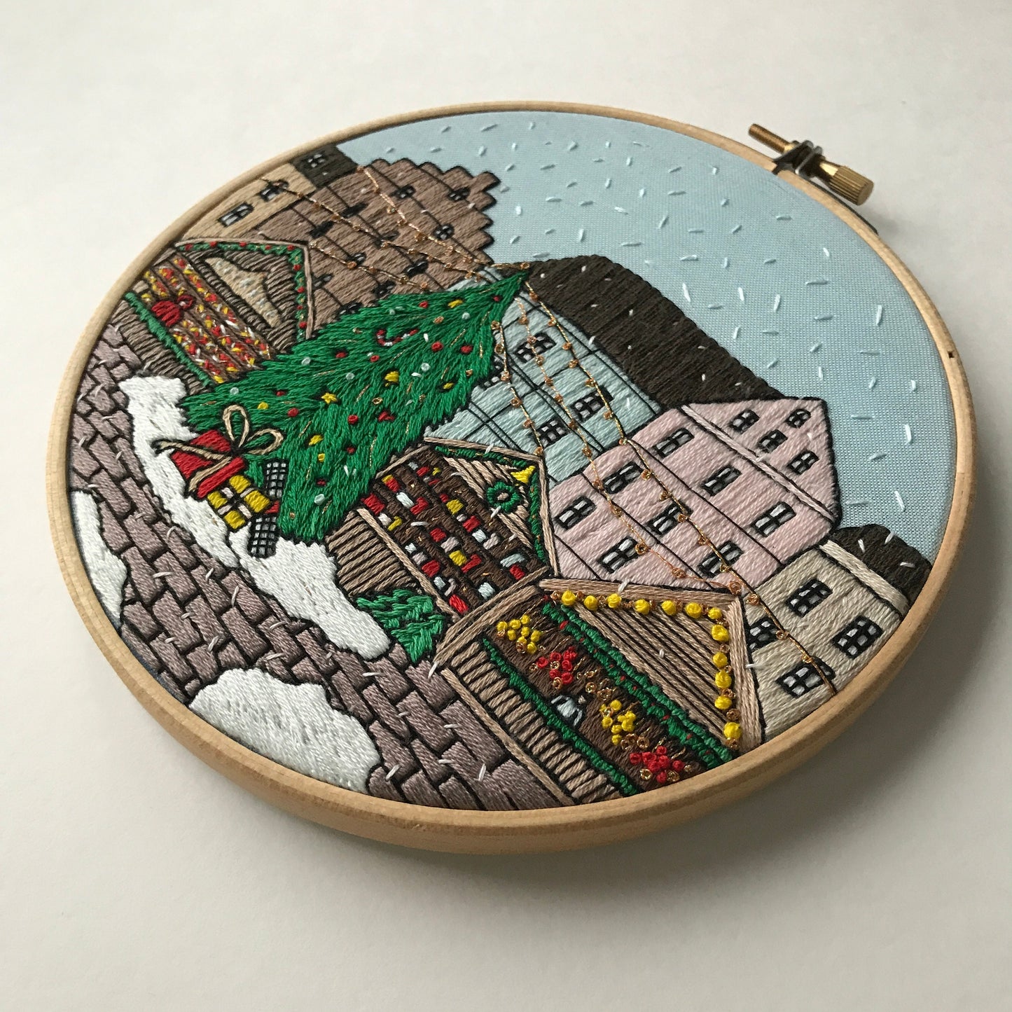 Embroidery hoop with a festive village scene on a light background