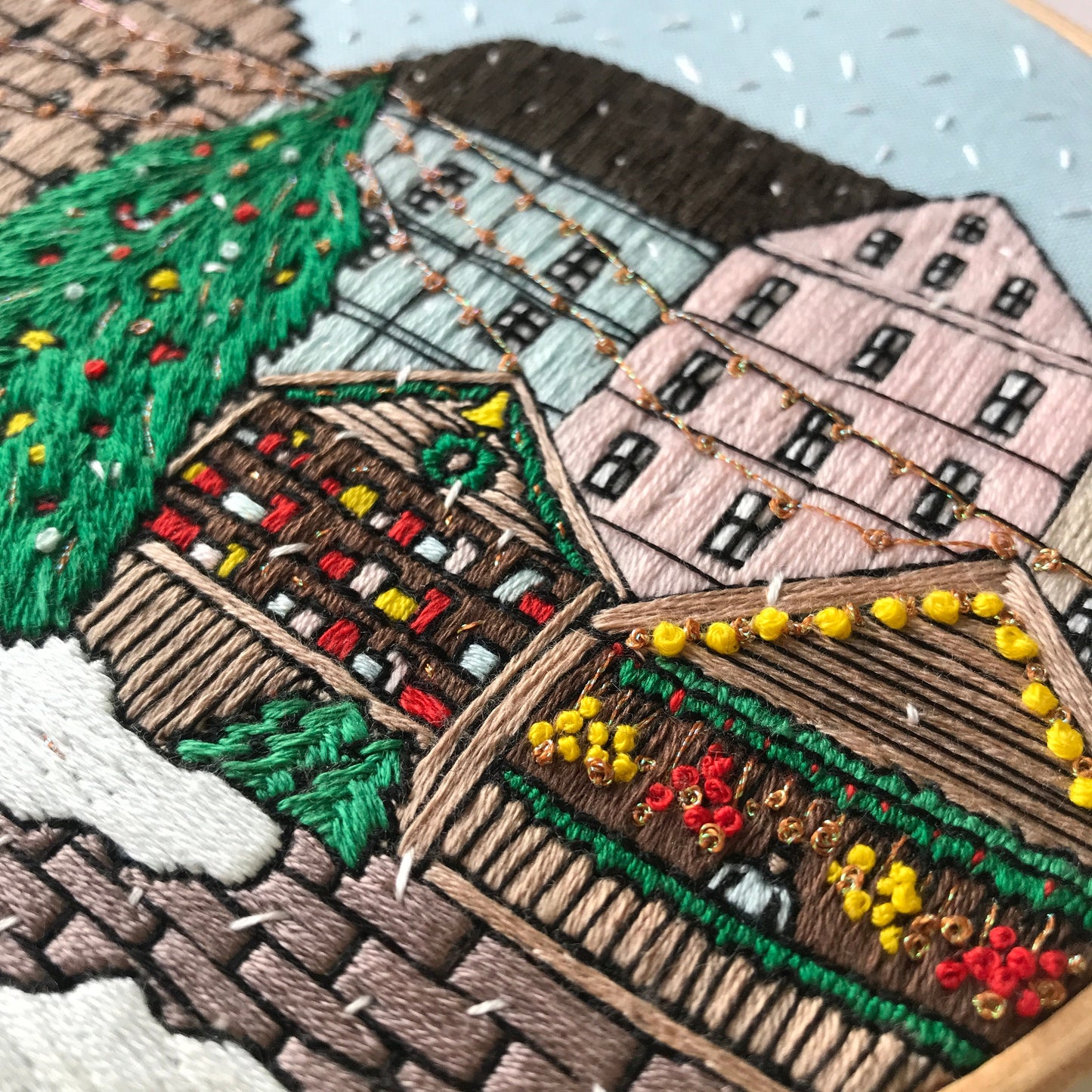 Embroidered scene of a village with houses and trees