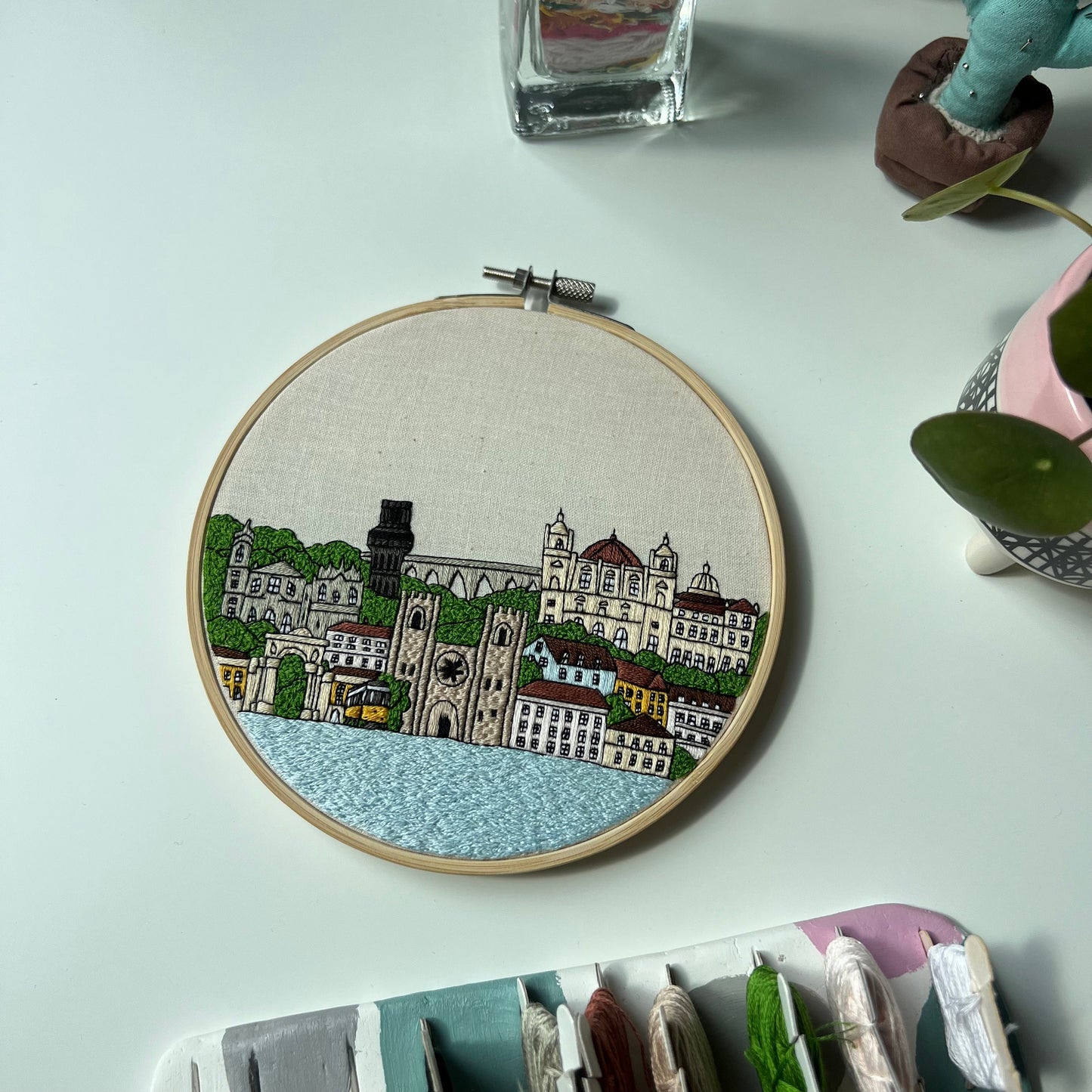 Embroidery hoop with a Lisbon cityscape design on a light blue surface