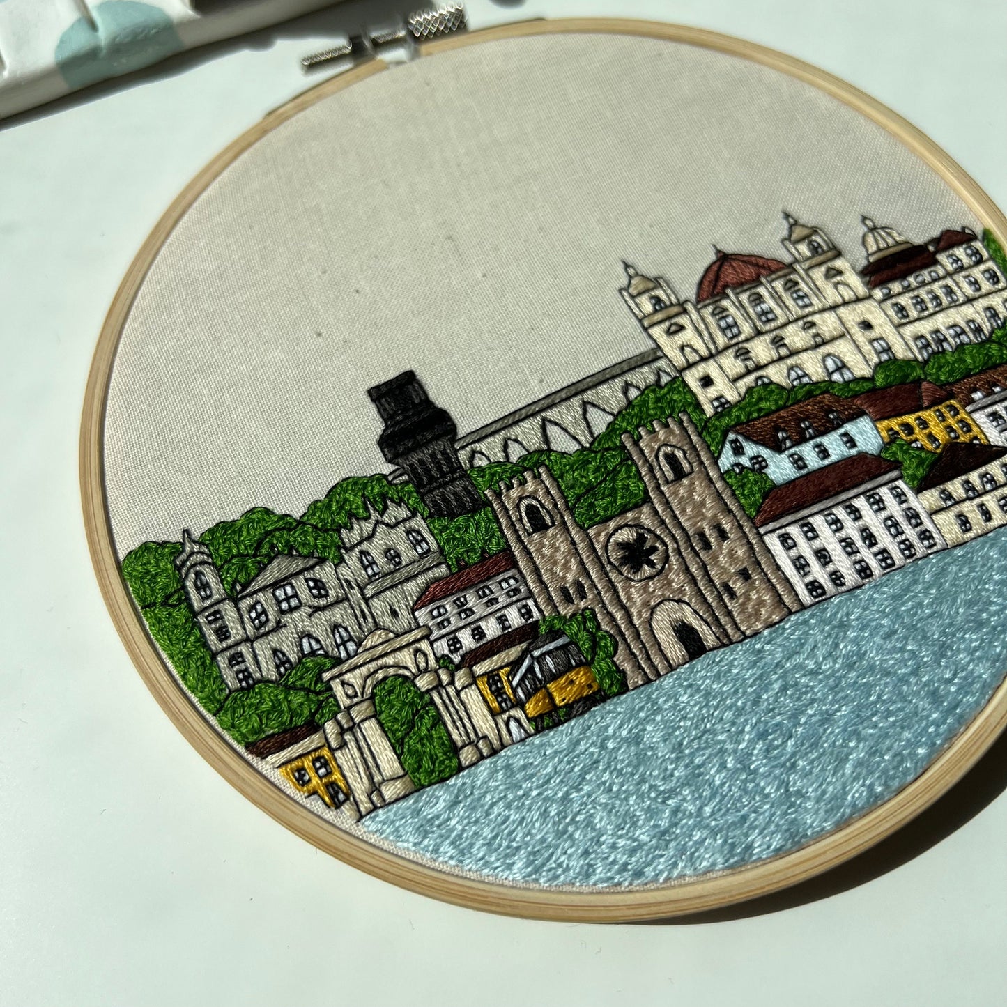Embroidery hoop with a Lisbon cityscape design on a light background