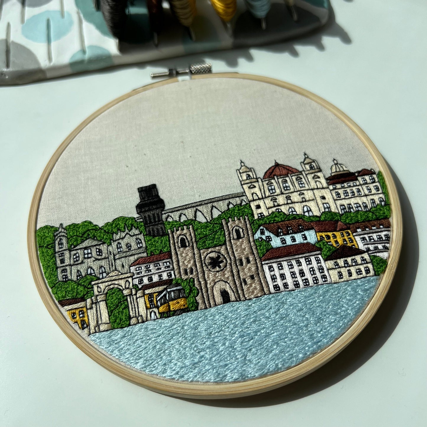 Embroidery hoop with a Lisbon cityscape design on a light background