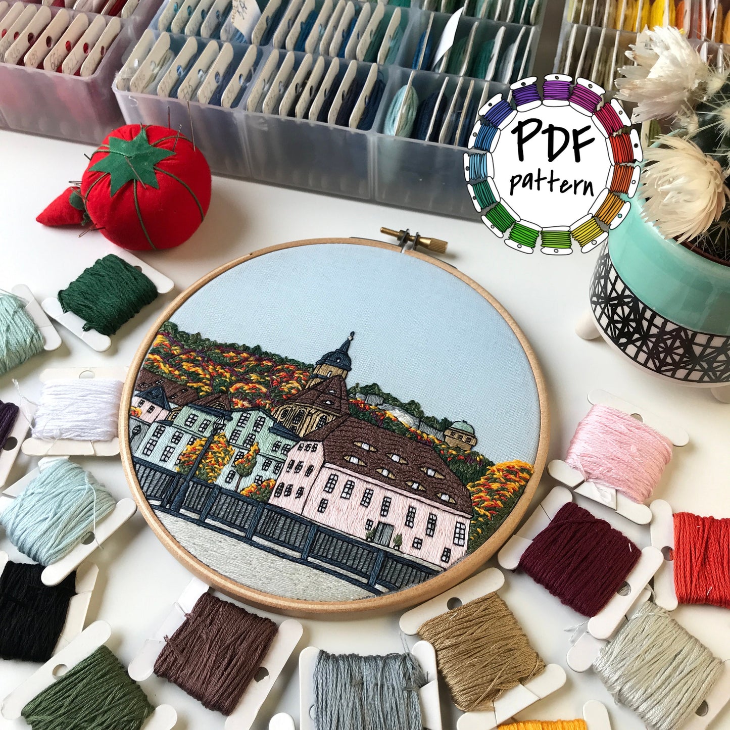 Hand embroidery pattern of Königstein forest and fortress with colorful threads and hoop.
