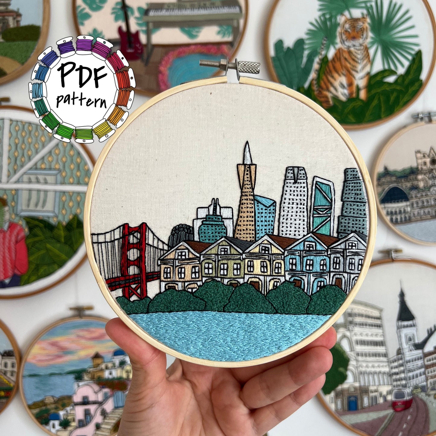 Hand holding San Francisco skyline embroidery in hoop with colorful threads