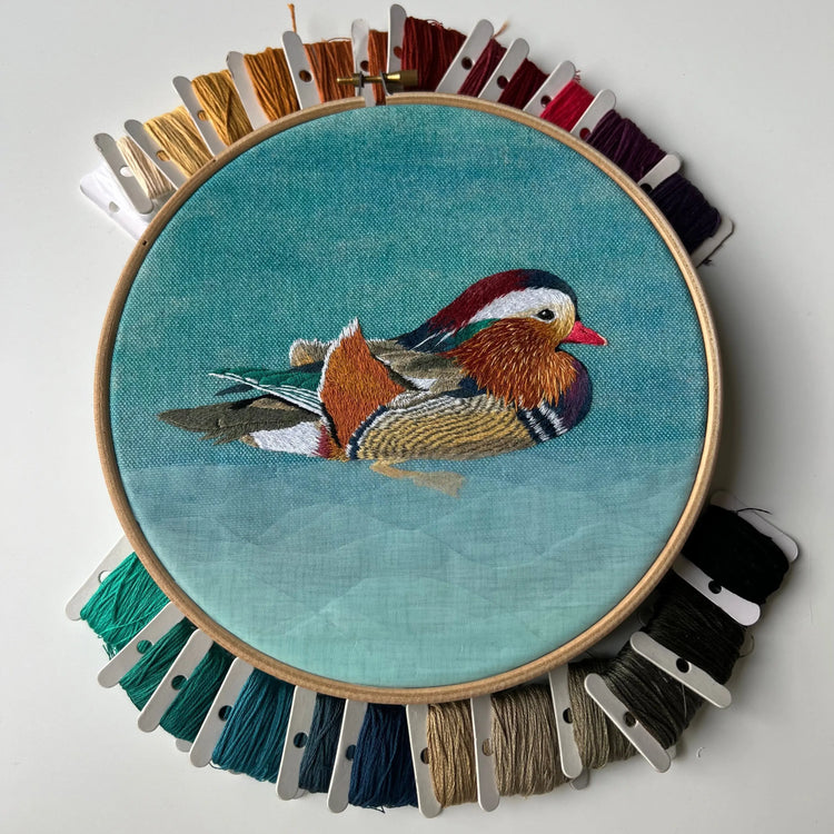 Whimsical Mandarin Duck embroidery pattern stitched in vibrant colors on linen fabric