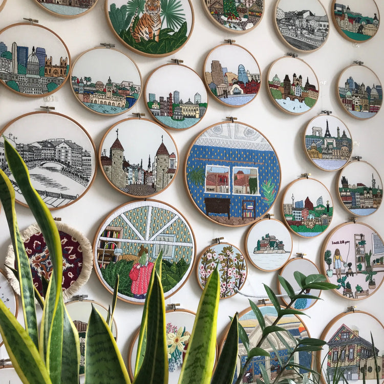 Colorful hand embroidery hoop wall displaying architectural and floral pattern designs