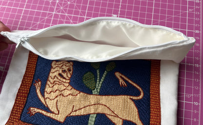 White pouch with zipper and embroidered medieval lion on a grid background