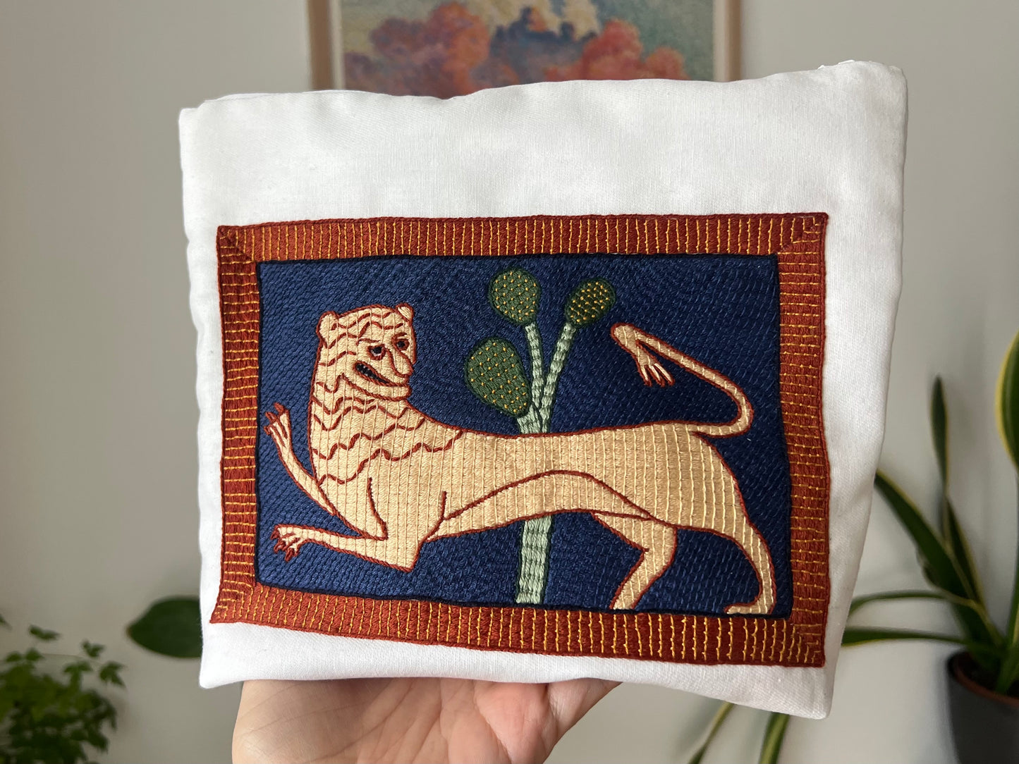 Embroidered lion design on a project bag with a blurred indoor background