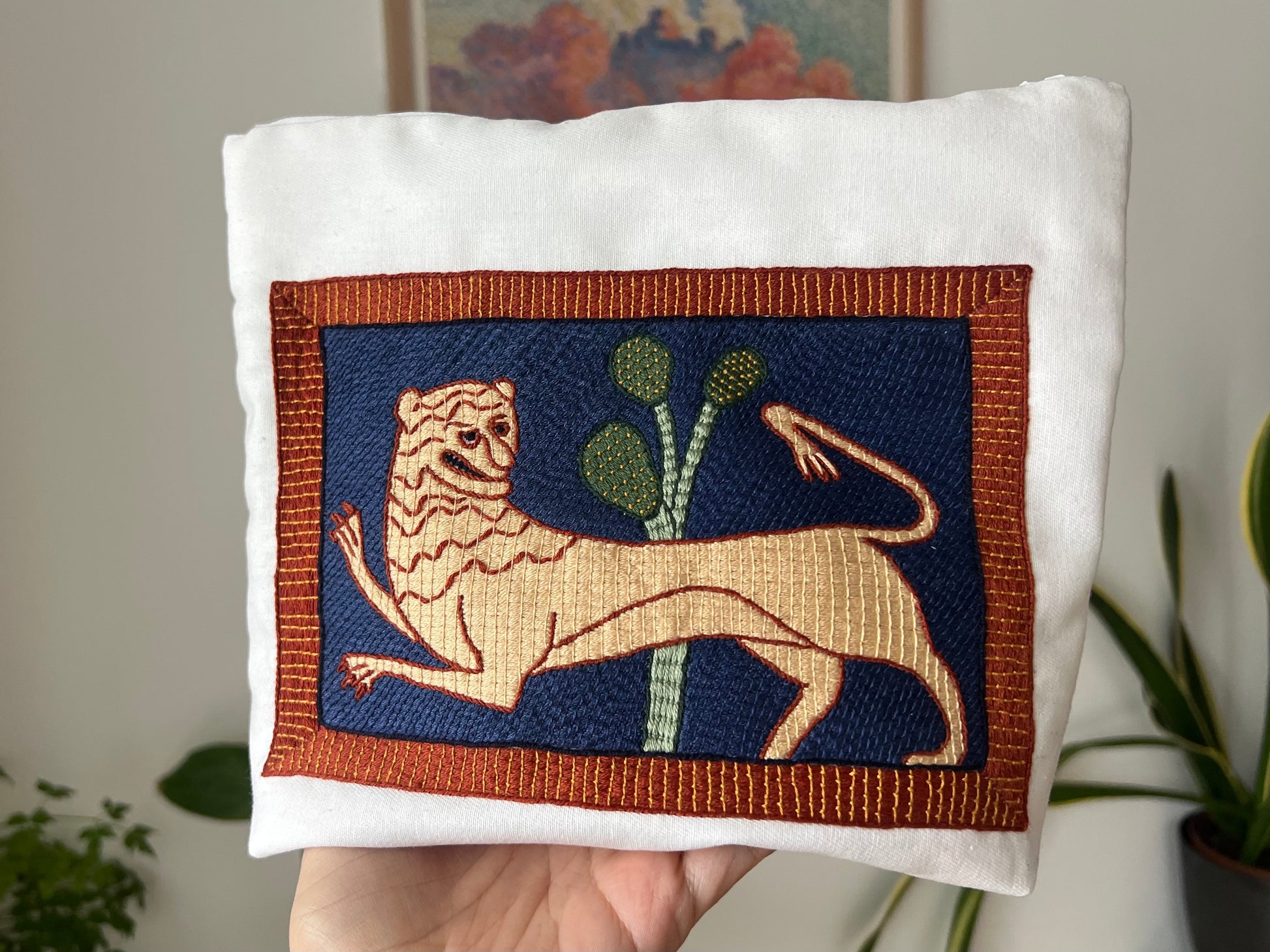 Embroidered lion design on a project bag with a blurred indoor background