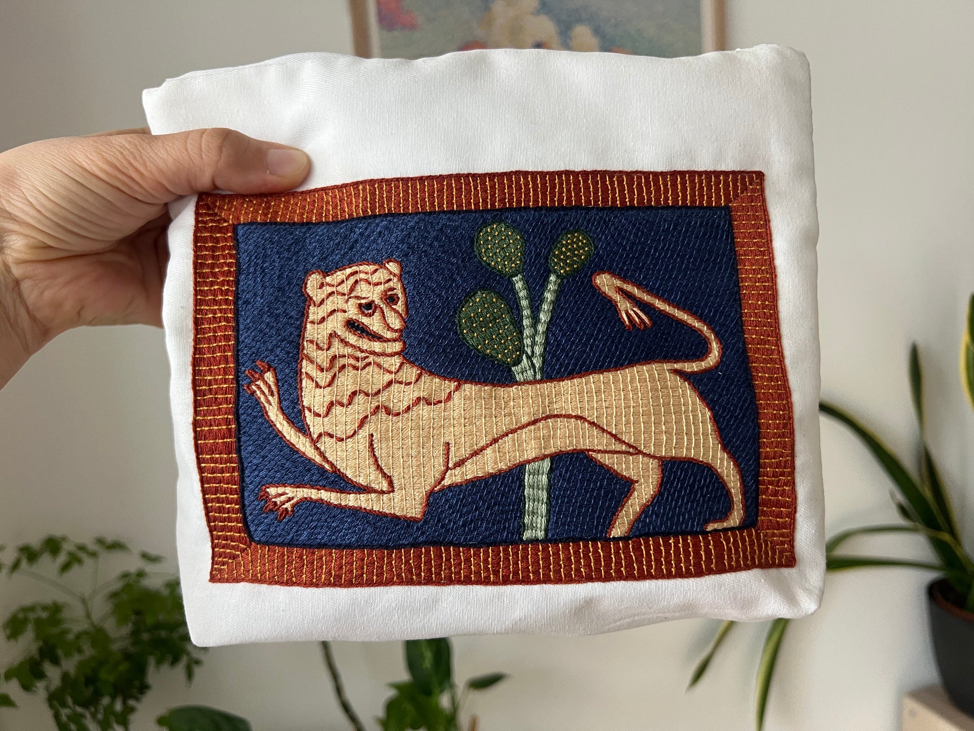 Hand embroidered patch of a lion with a plant on a white  bag