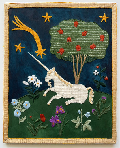 Embroidered artwork of a unicorn in a fantasy landscape with stars and flowers.