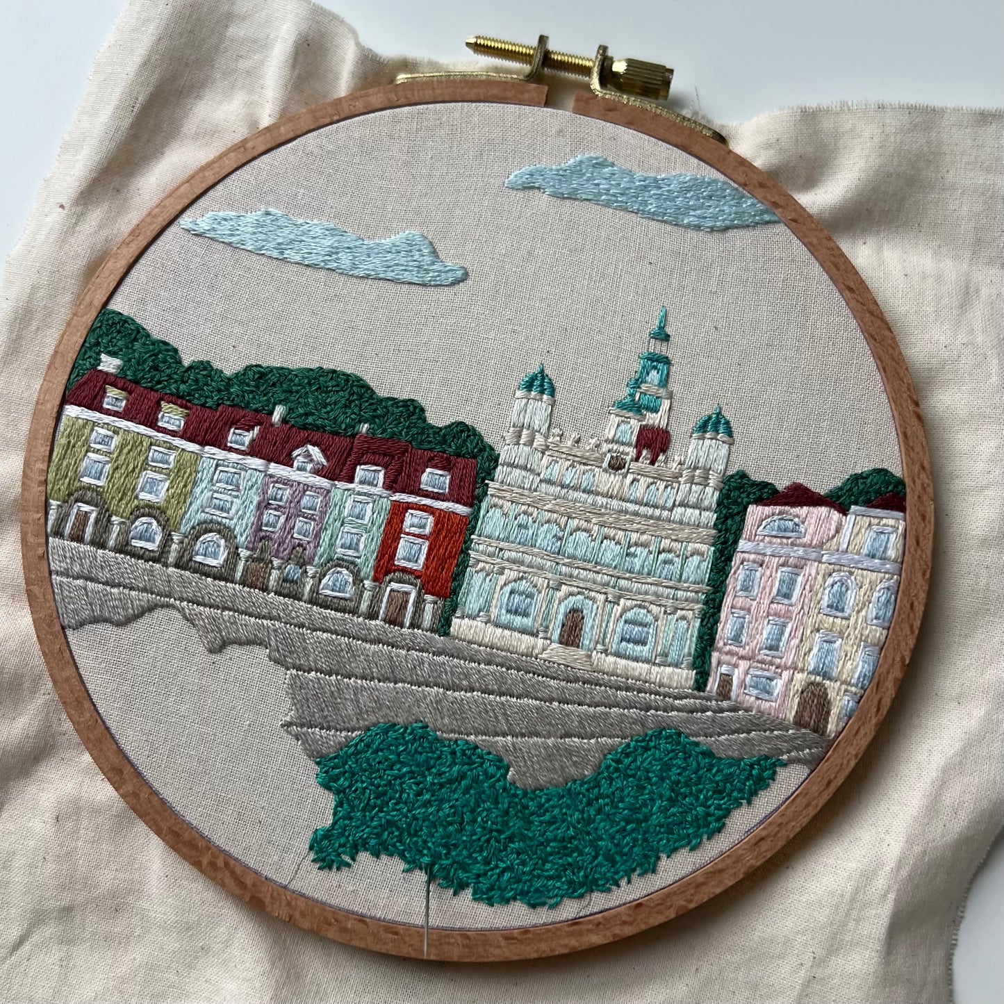 Embroidery of a cityscape with buildings and trees in an embroidery hoop. Process shot