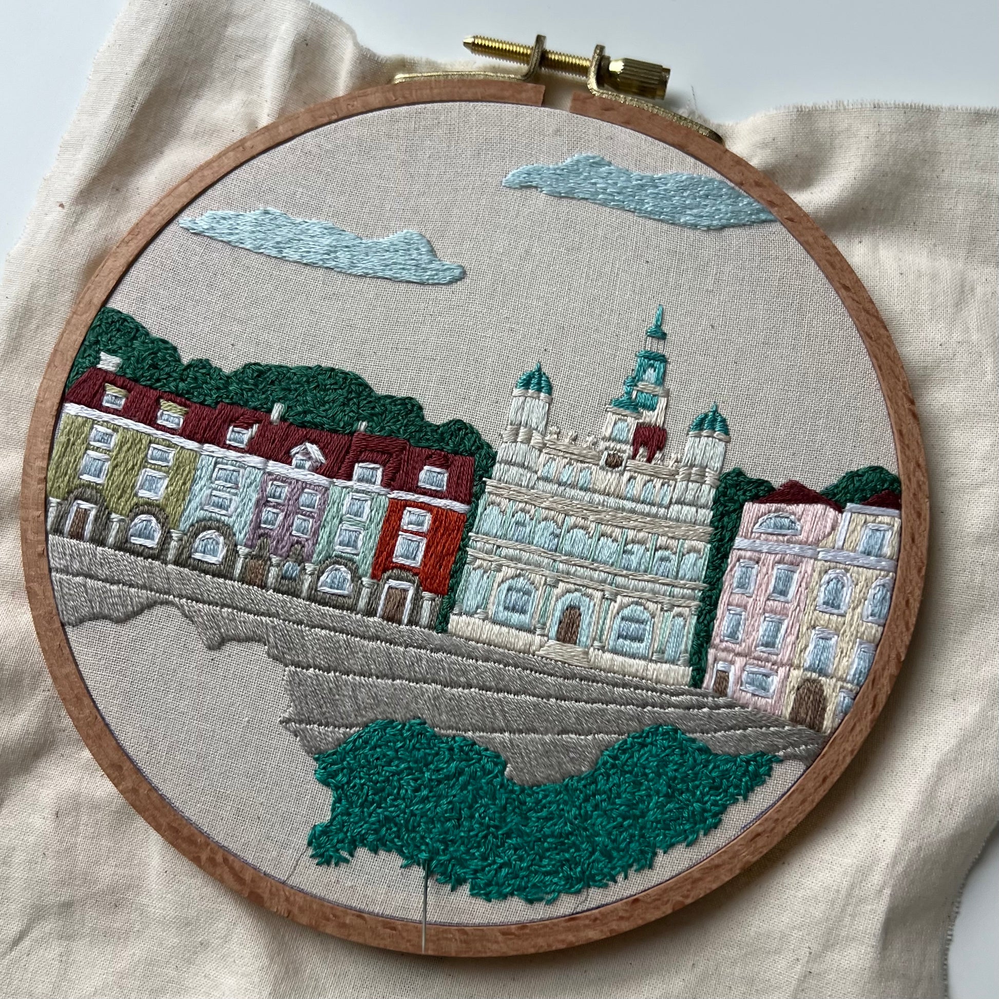 Embroidery of a cityscape with buildings and trees in an embroidery hoop. Process shot