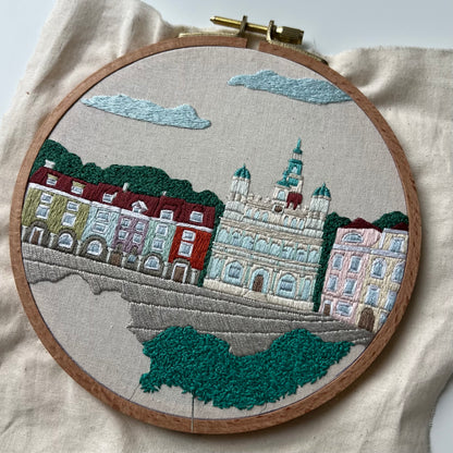 Embroidery of a cityscape with buildings and trees in an embroidery hoop. Process shot