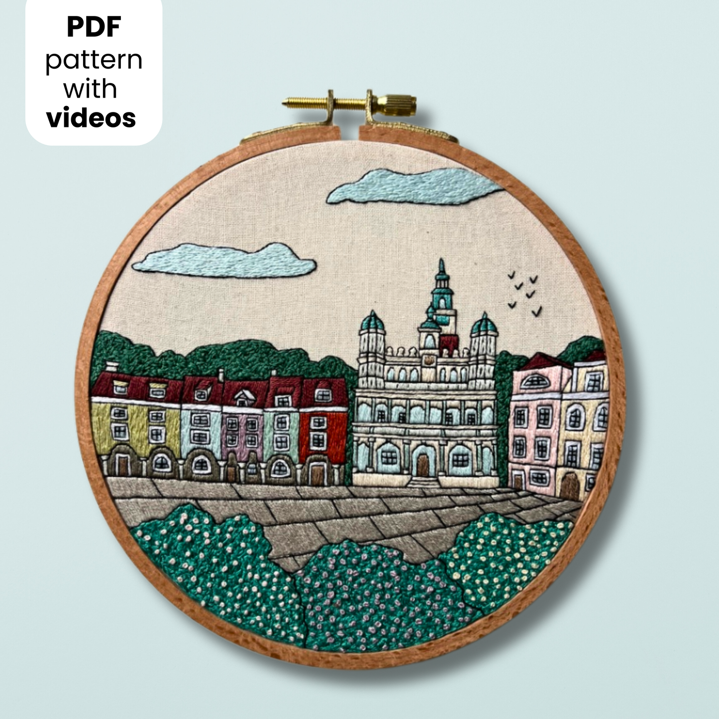 Embroidery hoop with a cityscape Poznan design on a light blue background