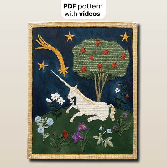 Embroidered artwork of a unicorn with flowers and stars on a dark blue background.