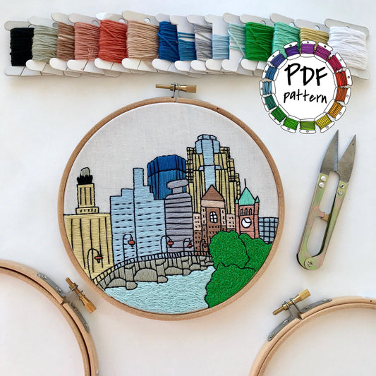 Hand embroidery pattern of Minneapolis cityscape with threads and tools, PDF download
