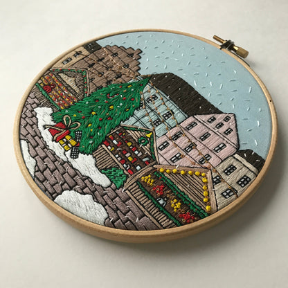 Embroidery hoop with a festive village scene on a light background