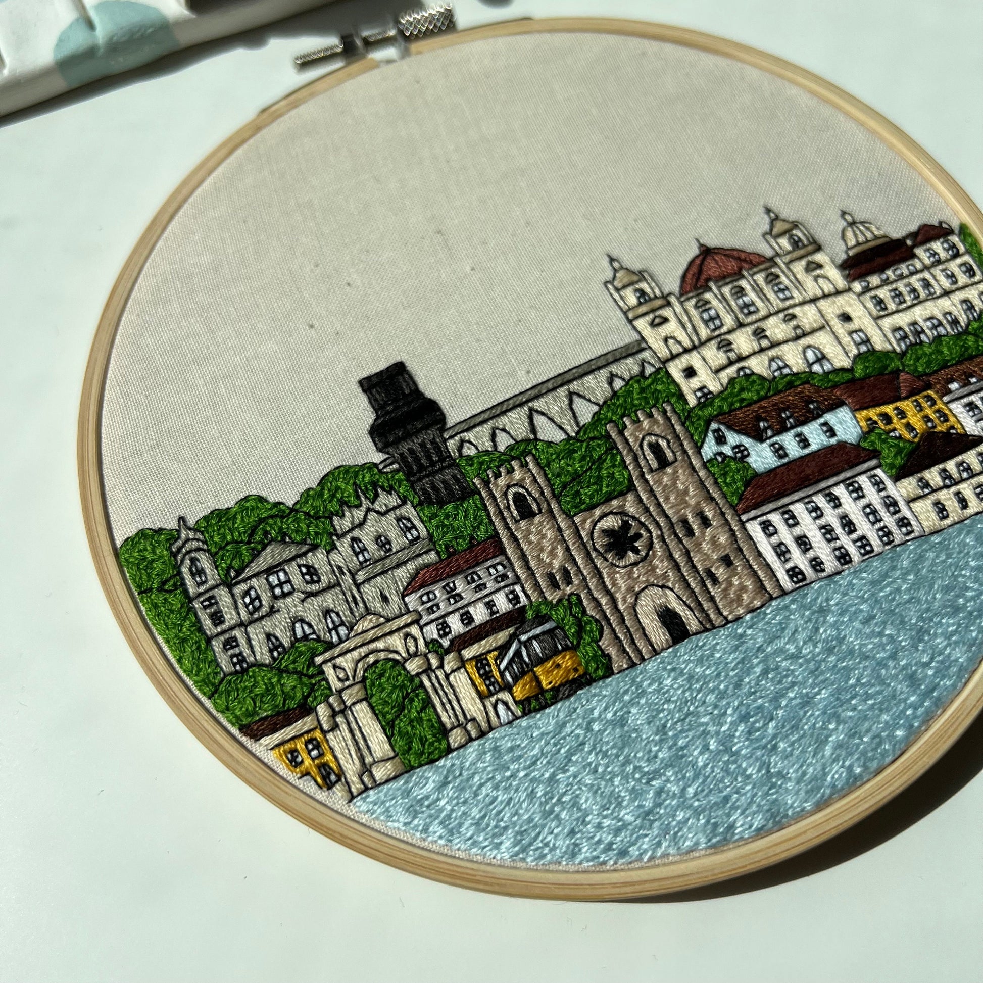 Embroidery hoop with a Lisbon cityscape design on a light background