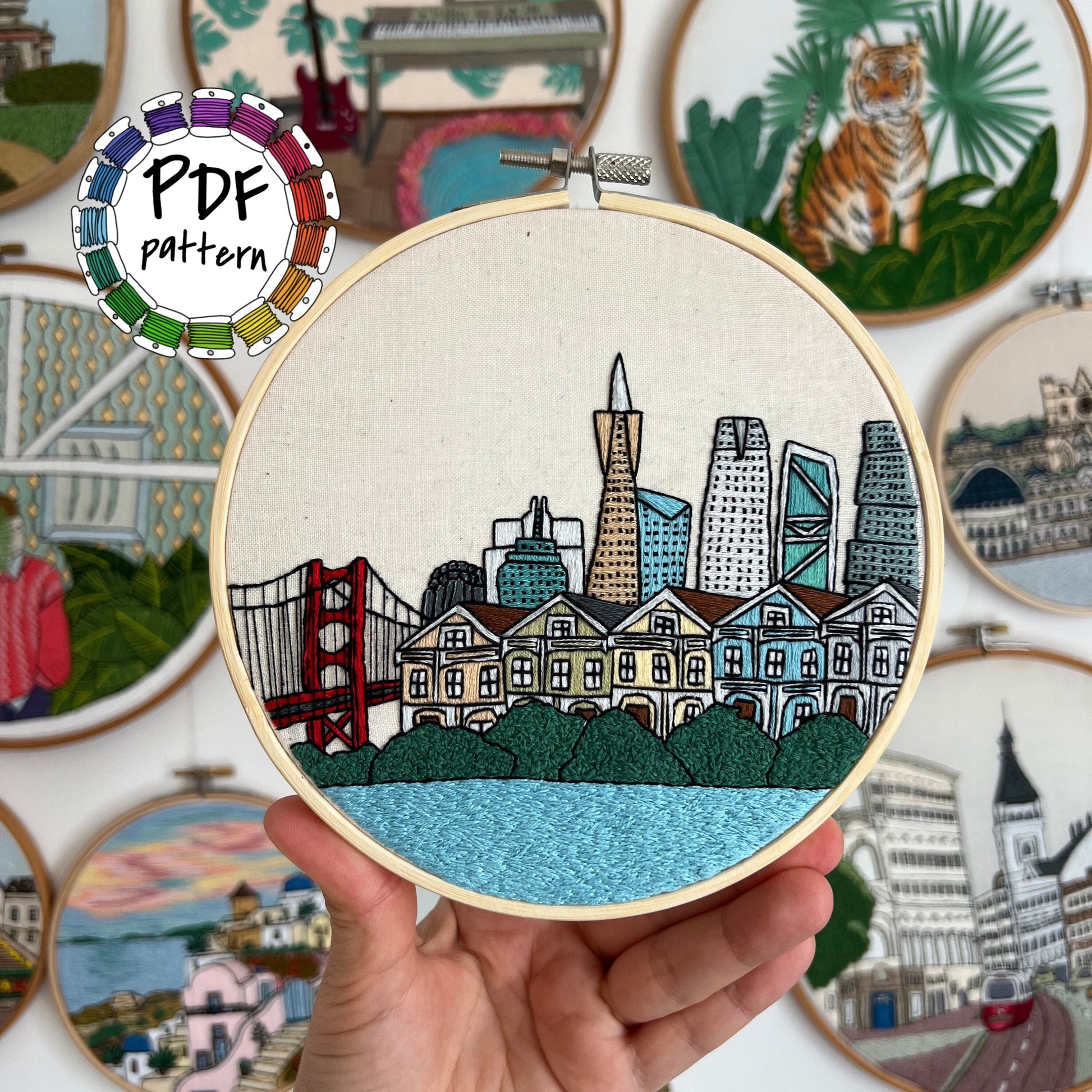 Hand holding San Francisco skyline embroidery in hoop with colorful threads